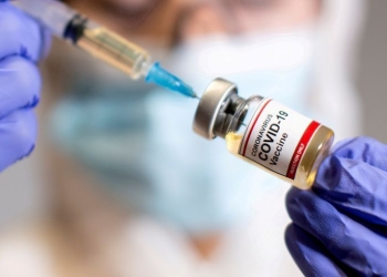 FILE PHOTO: A woman holds a small bottle labeled with a "Coronavirus COVID-19 Vaccine" sticker and a medical syringe in this illustration taken  October 30, 2020. REUTERS/Dado Ruvic